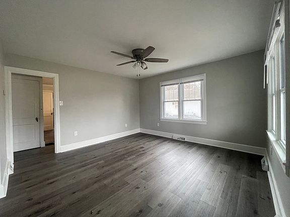New LVC flooring throughout the main level. New ceiling fans, light fixtures, and paint throughout. Doorway on left leads to kitchen to the right, basement stairs through the door, and bathroom and bedroom to the left.