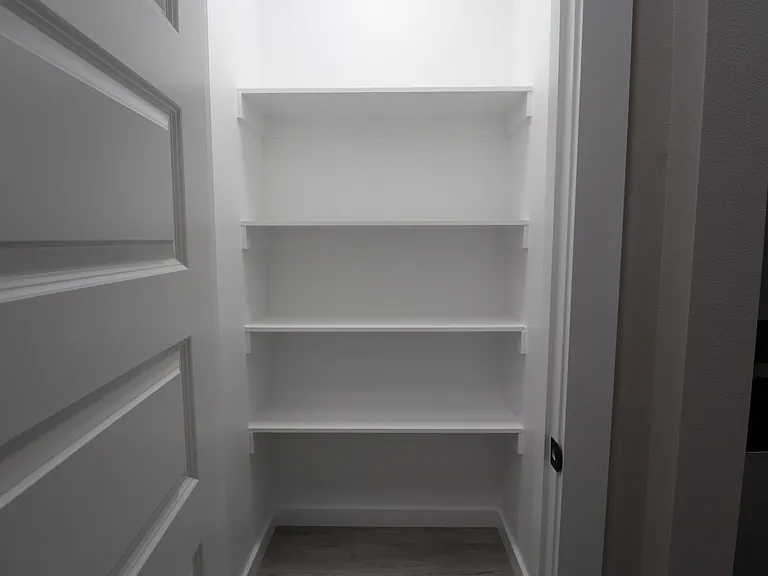 Spacious walk-in pantry offering ample shelving and storage, perfect for keeping the kitchen organized.