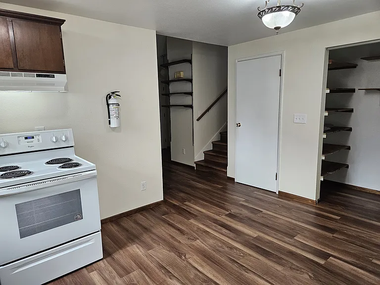 Main floor kitchen looking NW showing stove and pantry closet, and stairs to 2nd floor.