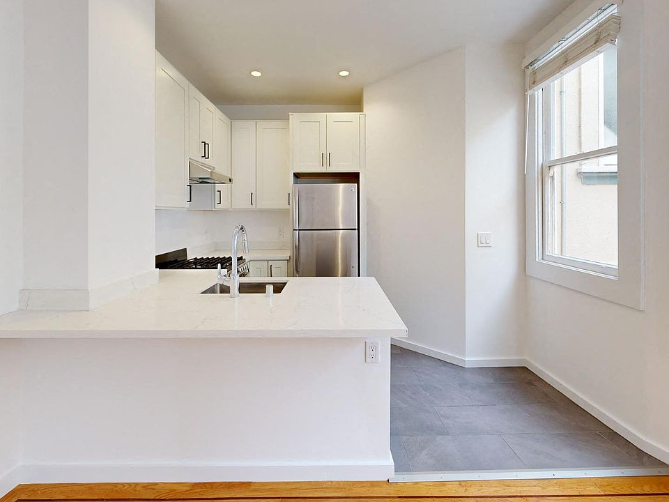 Kitchen with cabinets, refrigerator, stove, range hood, and sink