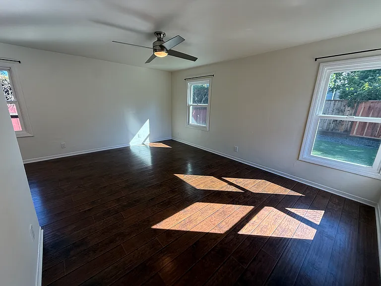 Bright, airy living room features multiple windows and hard surface flooring throughout.