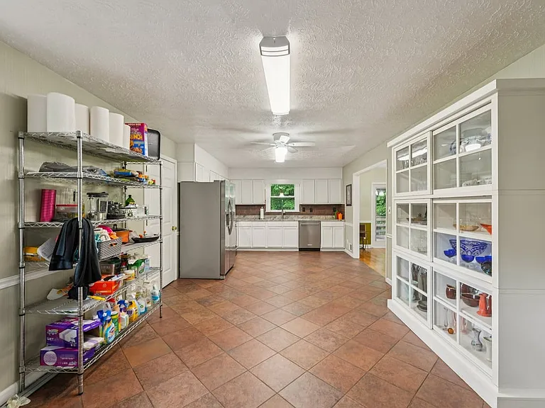 A cheerful multipurpose area where organization meets charm, featuring abundant shelving, easy care tile, and a bright, useful layout.
