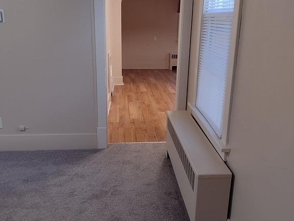 Newly carpeted living room with high ceilings, ceiling fan, mini-blinds, and valances.