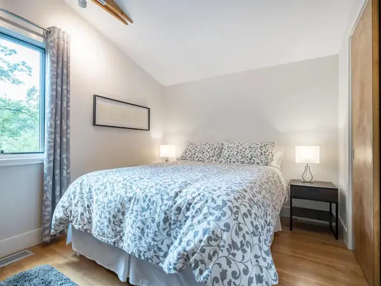 The queen-size bed fits comfortably in the bedroom, which has a full-wall length closet with sliding doors. The closet has a full-length hanging bar and shelf above. NOT included: artwork, linens, and rug shown.