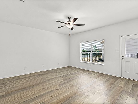 Spacious family room with a ceiling fan and large windows.