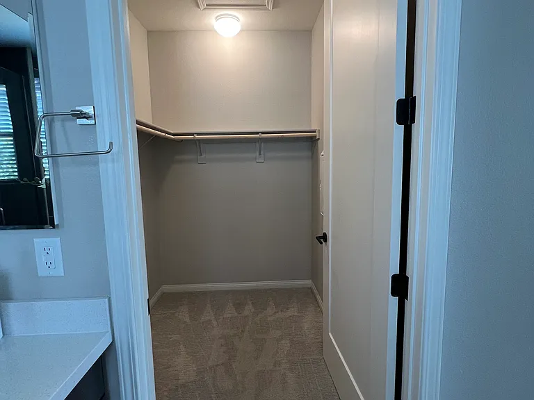 Spacious primary walk-in closet with additional shelving and storage behind the door.
