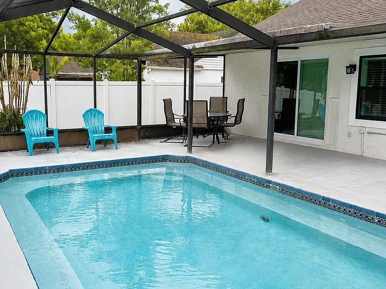 Screened-in patio with a private pool, fenced yard, and space for outdoor dining and seating.