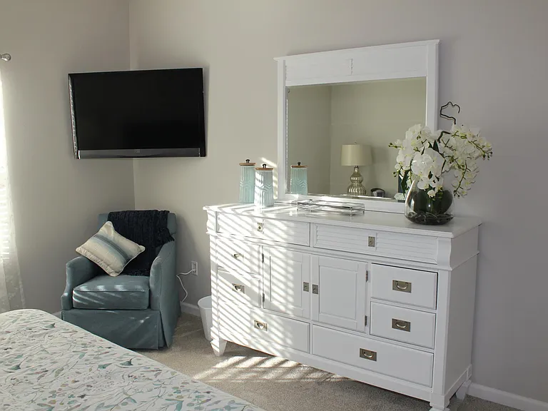 Large master bedroom with ample dresser storage and wall-mounted TV.