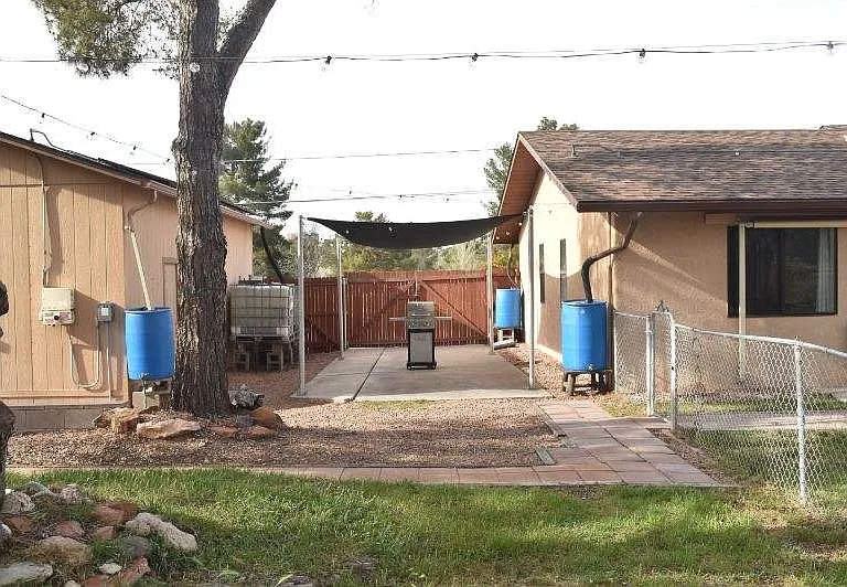 Grill and sunshade in portion of backyard.