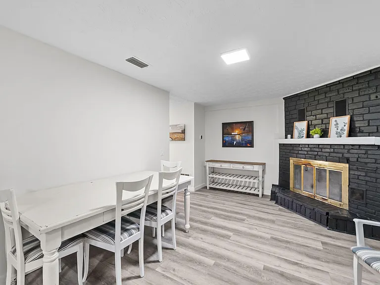 Dedicated dining area with a table set and a striking brick fireplace, plus durable flooring for easy upkeep.