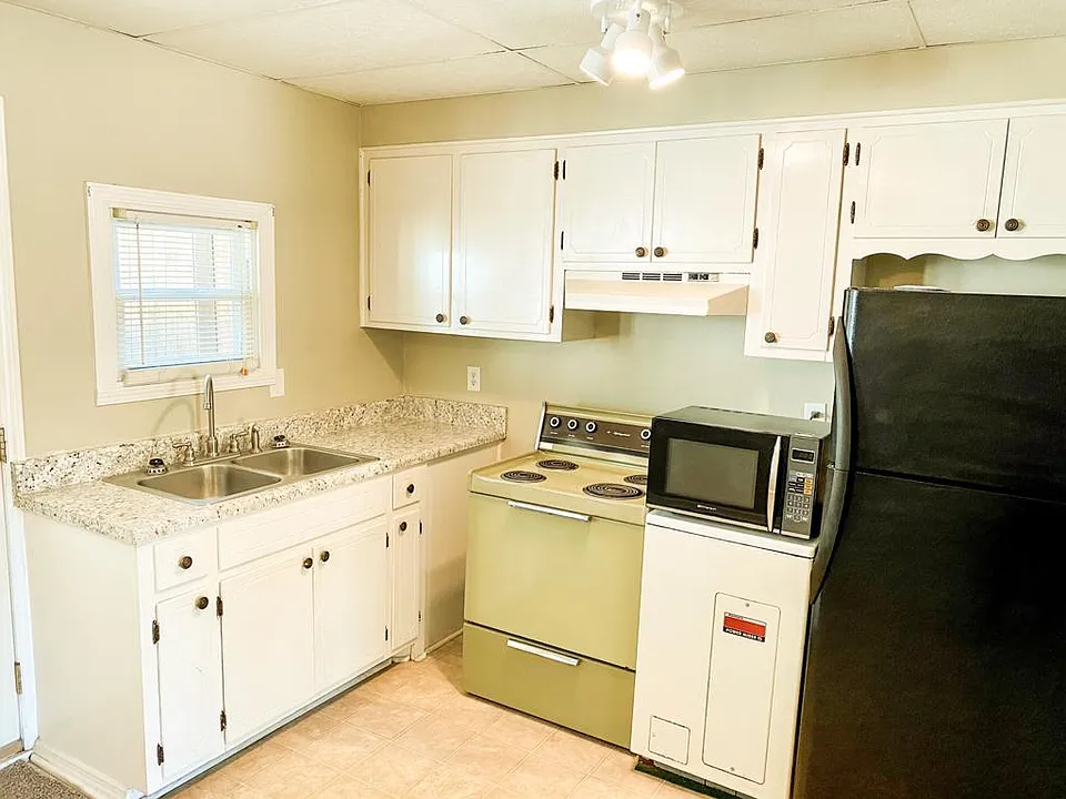 Kitchen, with brand new premium formica countertop. Box between stove and fridge (and below microwave) is the hot water heater.