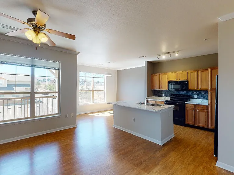 Apartment kitchen, dining and living room with wood-style flooring.