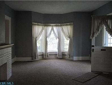 Living room with bay window and neutral carpeting.