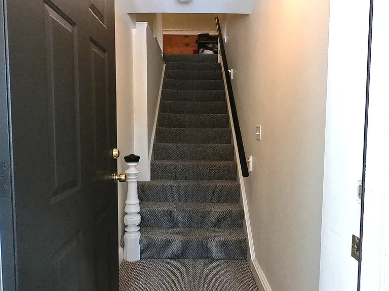 Looking up the staircase from the front entrance to the shared hallway on the second floor.