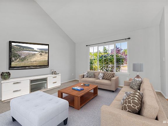 Digitally staged living room with vaulted ceilings>