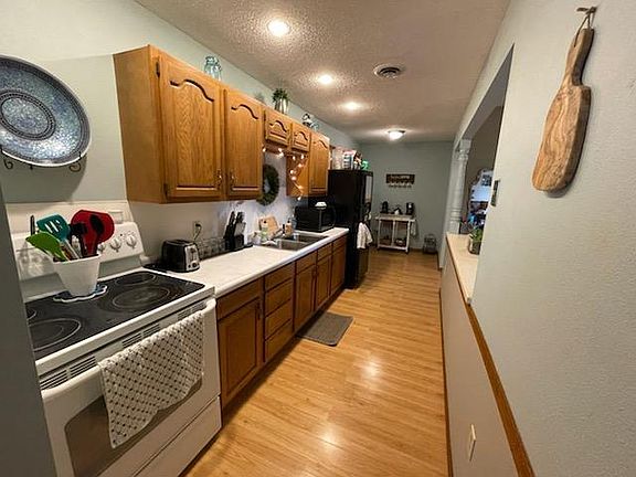 Galley kitchen with stove, fridge and microwave.