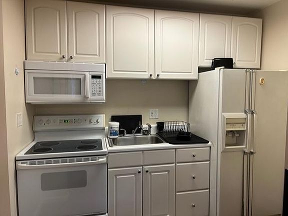 White kitchen with full size refrigerator , stove/oven and microwave Also has large toaster oven