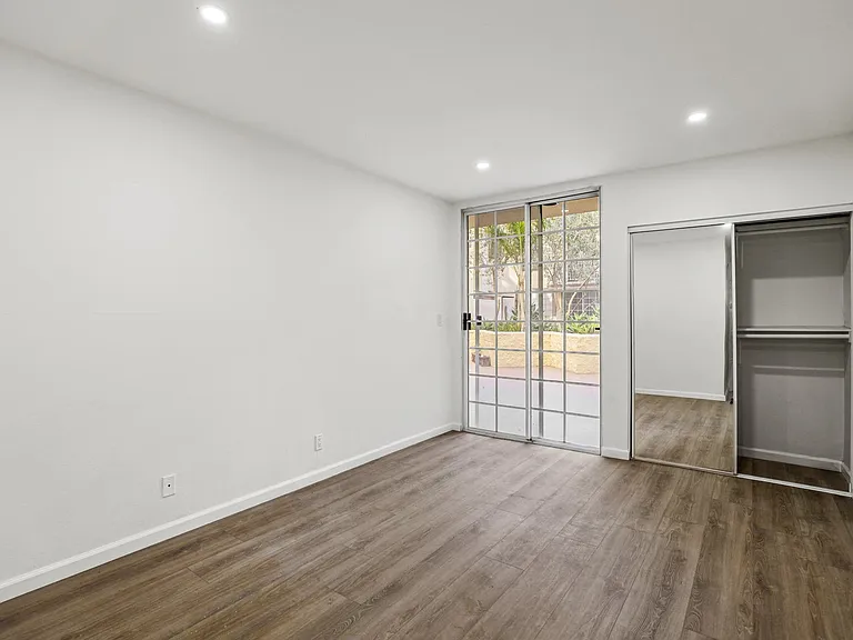 Bedroom with Mirrored Closet with Built-In Shelving and Patio