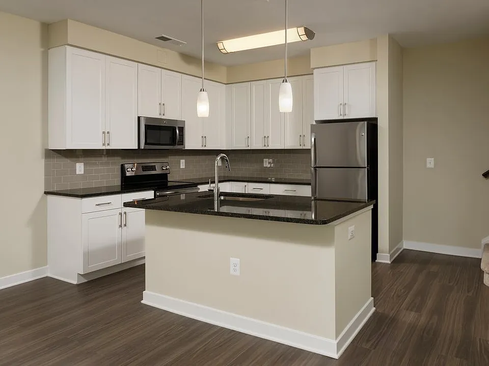 Townhome open concept kitchen with granite countertops and white shaker cabinetry, kitchen island, stainless steel appliances and hard surface flooring