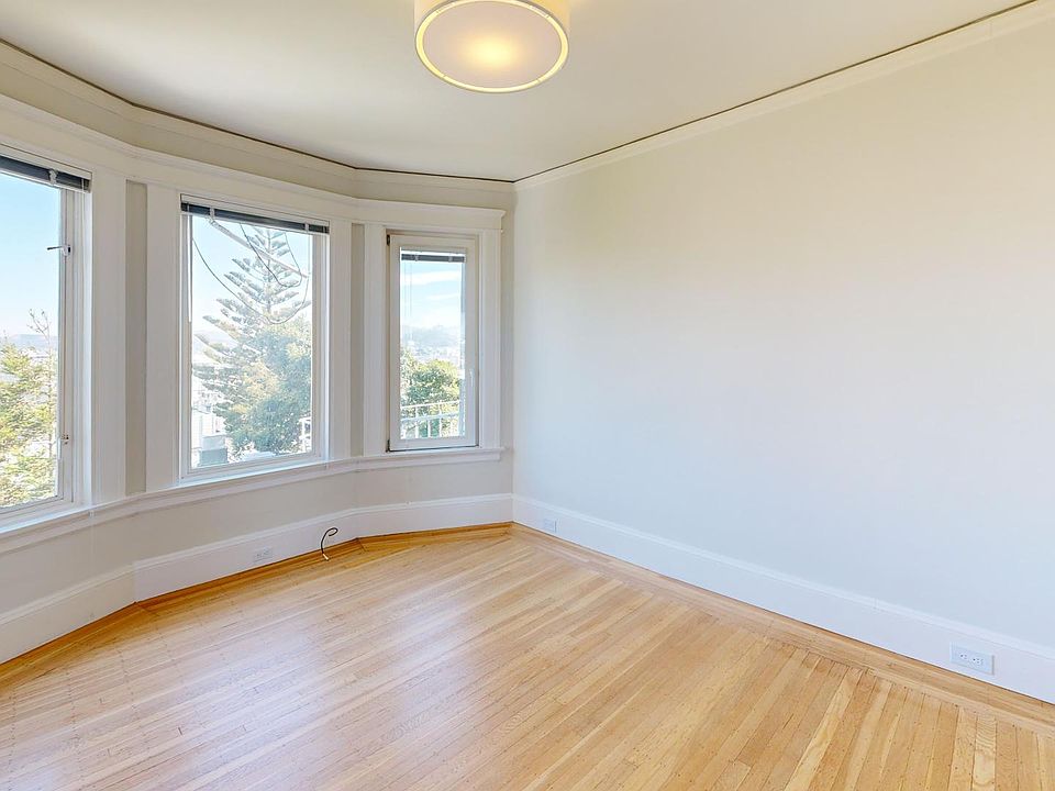 Spacious living room with wood-like flooring and a large window offering natural light