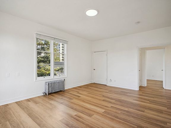 Sunlit room with a large window and wood-like flooring