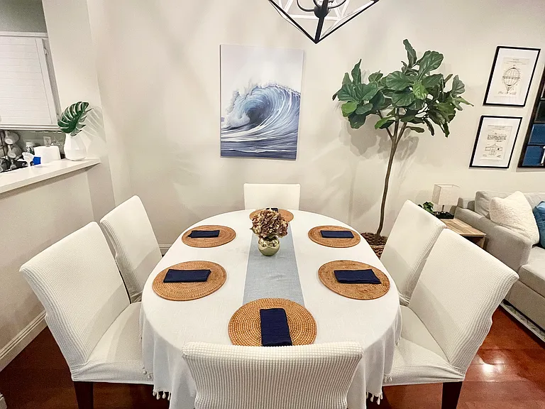 Elegant dining table for 4-6 guests with slipcovered chairs, overlooking the 65" Smart TV and connecting directly to the outdoor living and dining patio.
