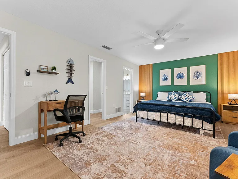Spacious bedroom with a dedicated desk area, ceiling fan, and nightstands, plus convenient access to an ensuite bath.