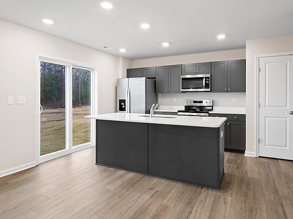 Island kitchen with gray cabinets and glass sliding door in a DRB Homes Glenshaw plan at The Village
