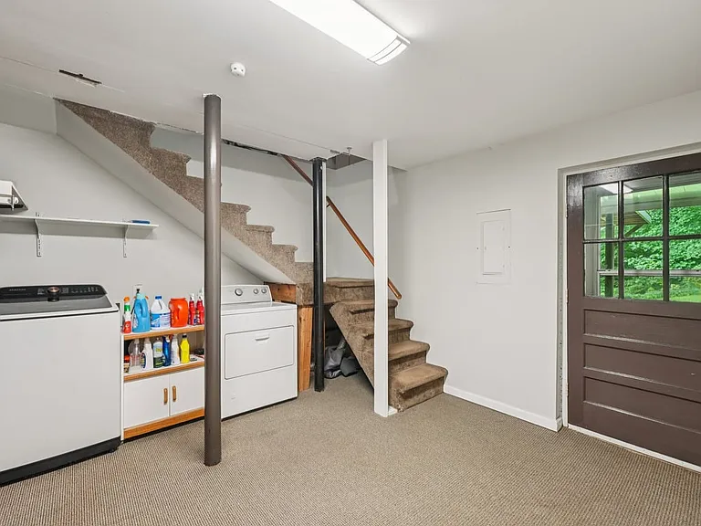 A practical lower level laundry area with private entry access, interior stairs, and everyday convenience, offering a functional space with quiet storybook simplicity.