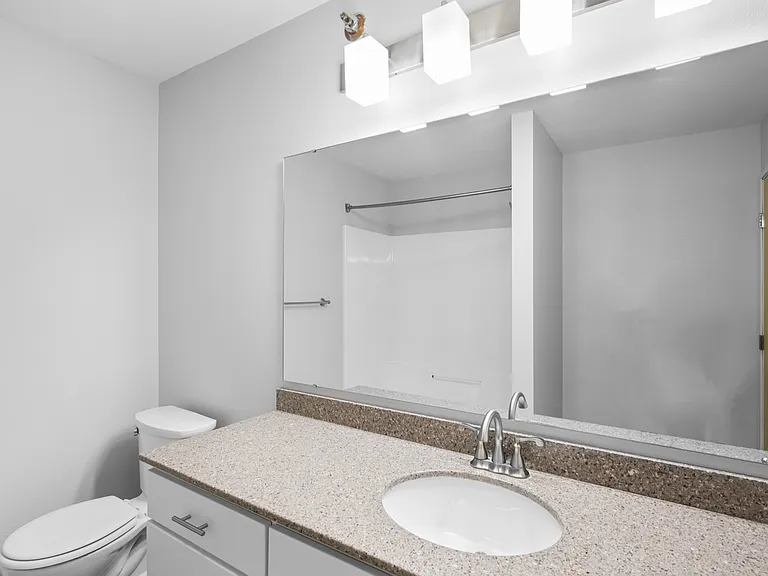 Modern bathroom with sleek granite countertop, large mirror, and elegant lighting. Modern bathroom with sleek granite countertop, large mirror, and elegant lighting.