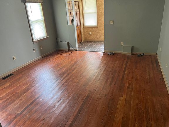 Living room facing front door. Large windows and wood floor.