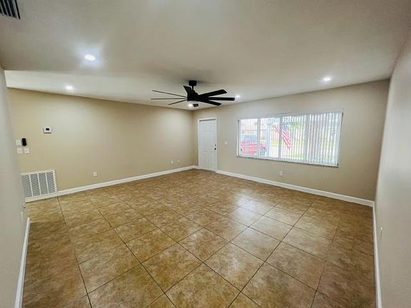 Large tiled living room with ceiling fan.