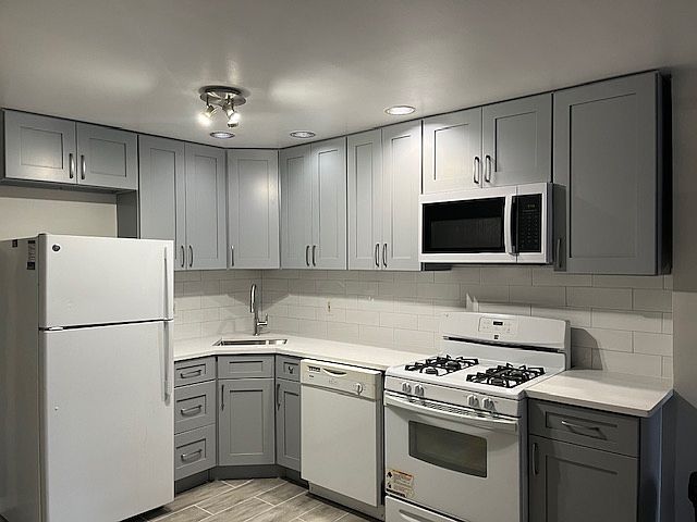 newly updated kitchen with refrigerator, dishwasher, oven and gas range.