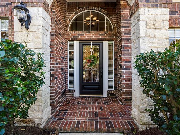 This view of the front door provides a closer look at the way the brick & stone compliment each other. The GORGEOUS glass paned front door is accented by fluted trim, mirrored sidelight windows, & crowned by an arched window above.