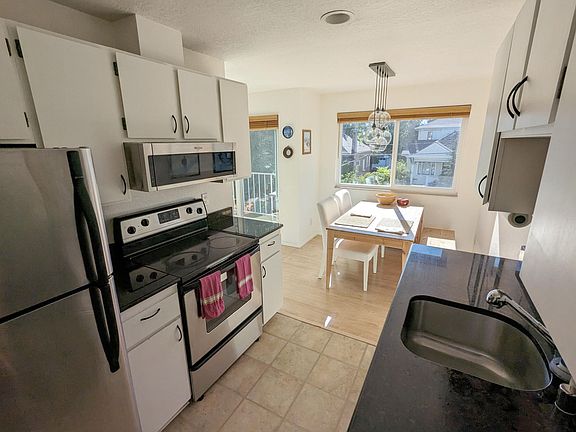Kitchen and dining. Appliances include dishwasher, microwave, oven, and garbage disposal. Note: the pendant light in the dining room has been replaced with a flushmount since this photo was taken.