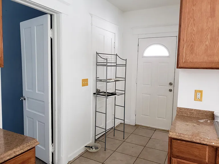 Back Hall with entrance to 3rd Bedroom on the left, Basement door, middle, Door to back yard. Unseen: Bathroom door on the right. Shared basement storage with private access to basement.
