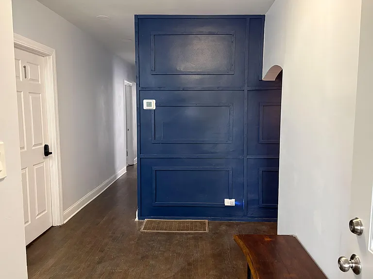 Entry hallway with wood-style flooring, crisp trim, and a bold accent wall that adds character and definition.