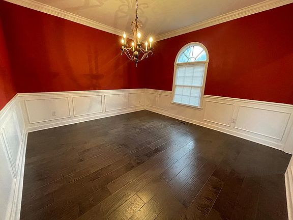 Formal dining room with hardwood floors, chandelier and wainscoting.