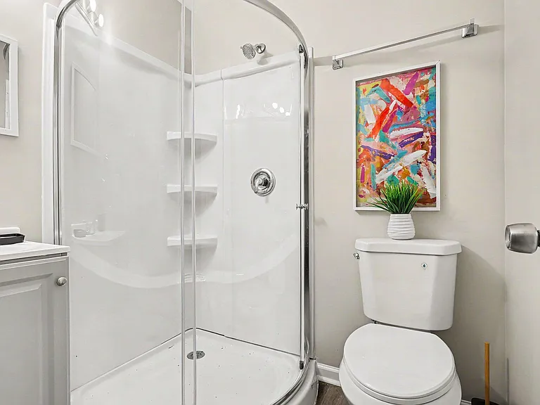 Clean bathroom with a corner glass-enclosed shower, vanity sink, and updated fixtures for everyday convenience.