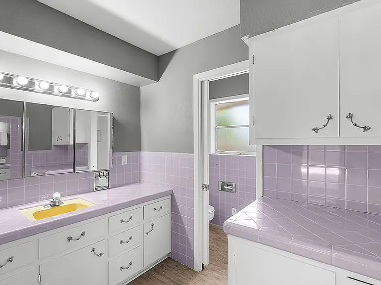 Primary bathroom with great lighting; medicine cabinet storage behind mirrors, lots of storage cabinets and built-in clothes hamper