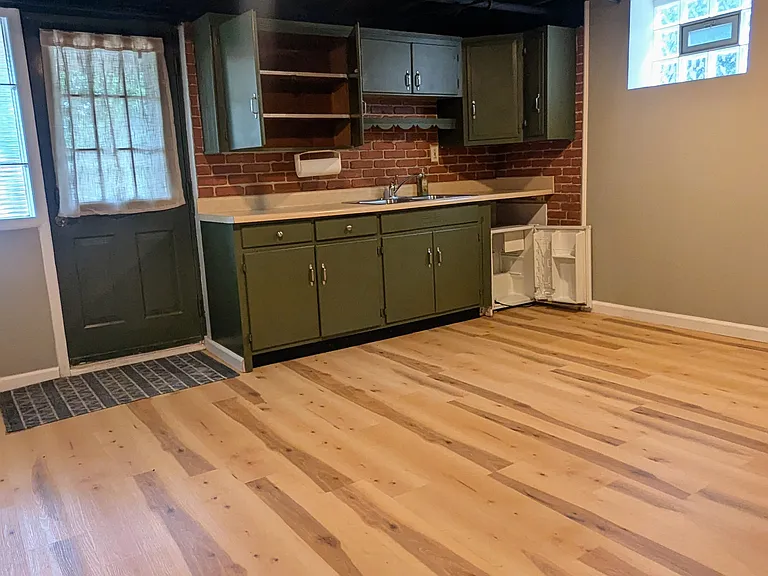 A small kitchenette area with sink and small refrigerator are in the main area of the basement.
