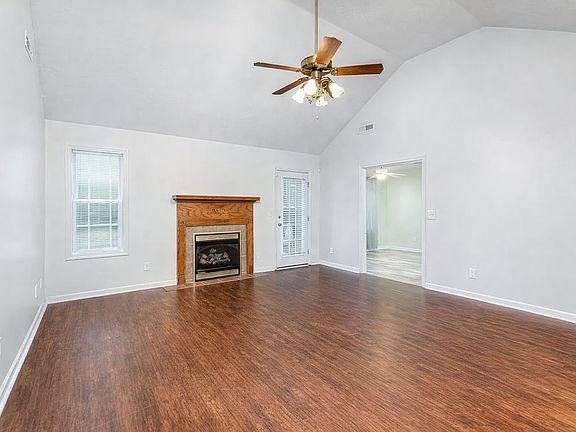 Living room with gas fireplace. Kitchen is opening to the right and backyard is viewable from the window and door.