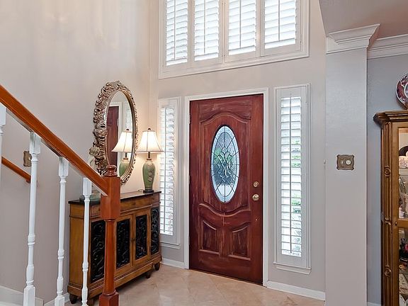 The foyer includes ceramic tile floors, high ceilings, crown moulding, a beautiful wood-stained beveled glass front door with sidelights. A beautiful staircase leads to the second floor with a balcony view from above.