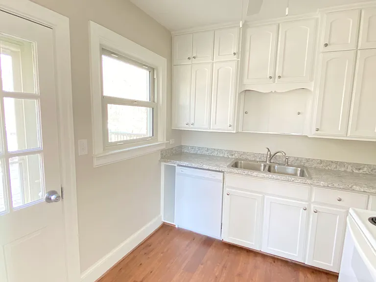 Bright white kitchen with ceiling fan and door to deck
