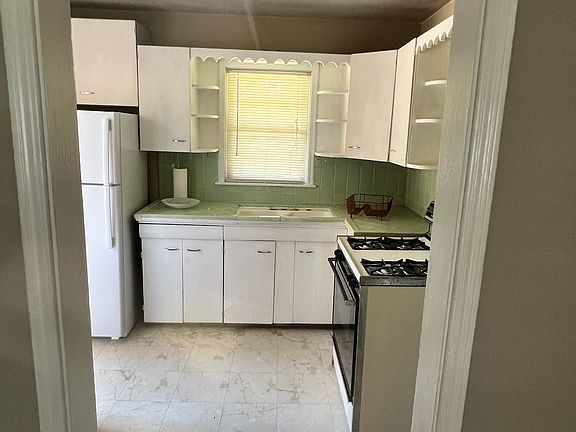 Looking into the kitchen from the main living/dining area. Door to backyard/garage is to the left of the fridge.