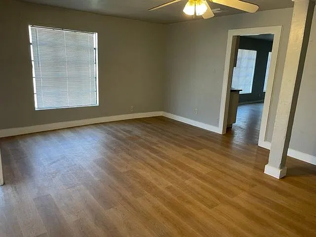 Large open living room with new floors and fresh paint.