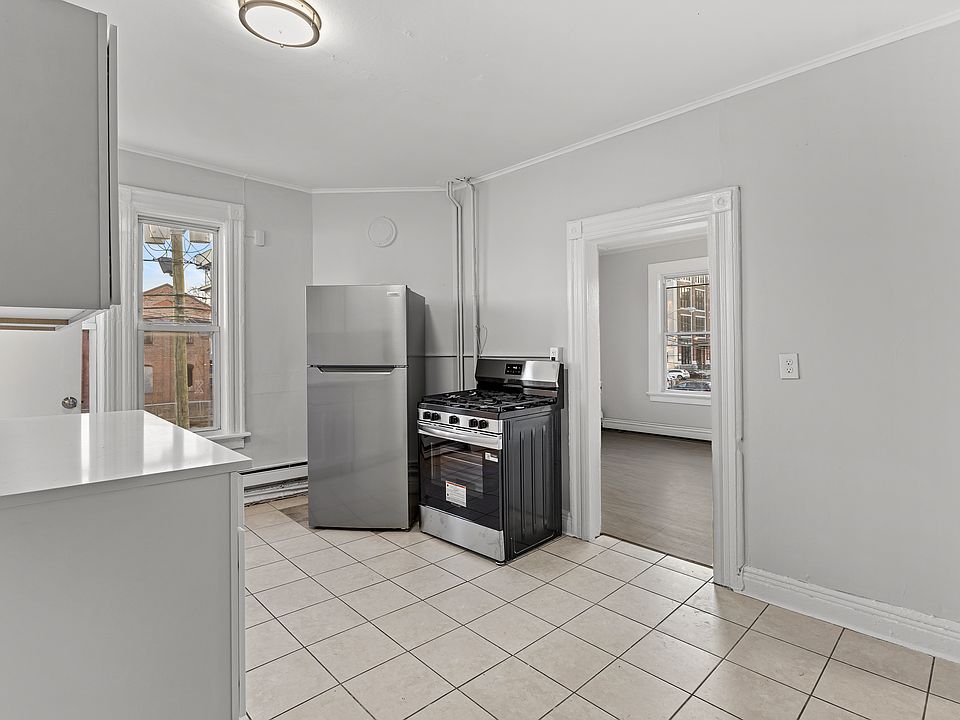 Spacious eat_in kitchen with ample white cabinetry, generous counter space, and tile flooring throughout. Large windows bring in natural light, offering a bright and welcoming space for everyday dining.