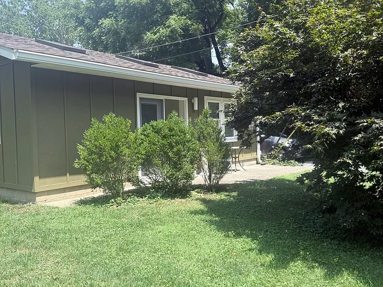 View of carriage house from SW showing back patio, back door and windows into living room.