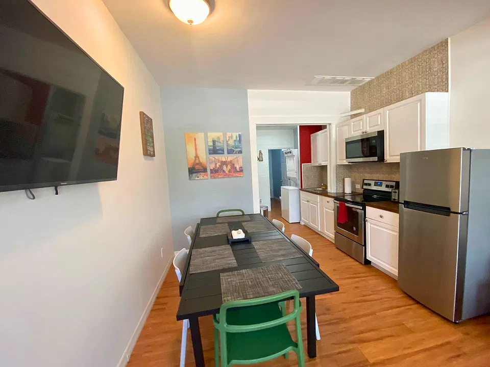 Bright dining room with 6 chairs and their respective placemats and TV