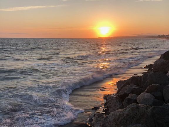Sunset over Dana Point walking along the beach in front of Mariposa. Sun setting over Dana Point.